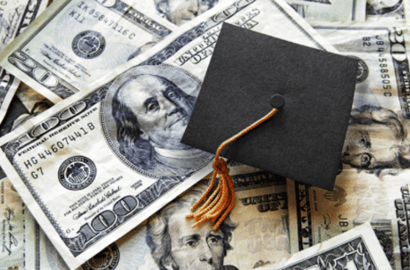 Money spread out with mini graduation cap set on top