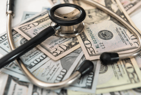 Stethoscope on top of $50 and $100 dollar bills