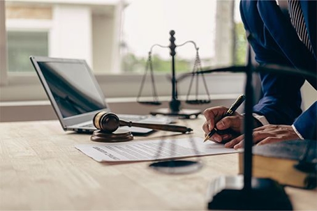 Lawyer desk with laptop, gavel, documents, and scales of justice.