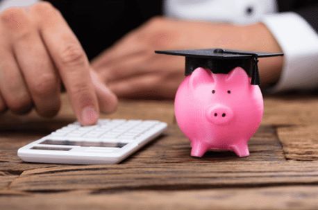 man using calculator next to piggy bank