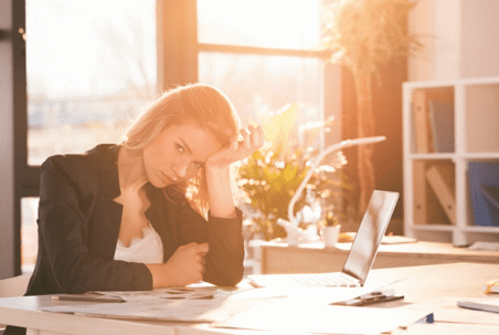 woman at desk with head in hands