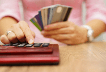 woman hands holding credit cards and using calculator