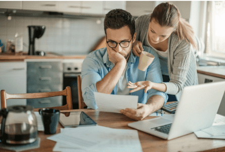 woman leaning over mans shoulder in kitchen reviewing document