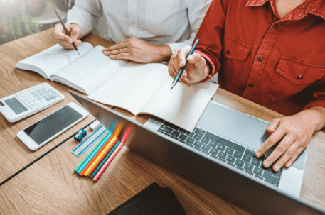 man and woman at desk with notebooks and laptop
