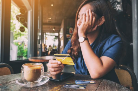 woman in coffee shop holding credit card