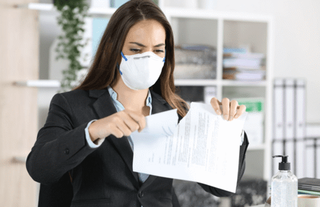 woman in mask ripping up document