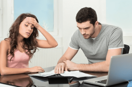 man and woman stressed looking at documents with laptop