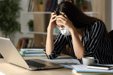 woman leaning over laptop with mask