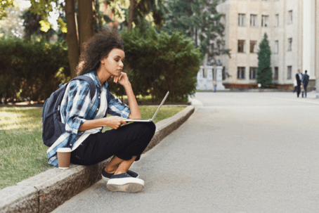 young woman sitting on curb in college