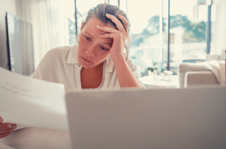 woman holding head looking at document