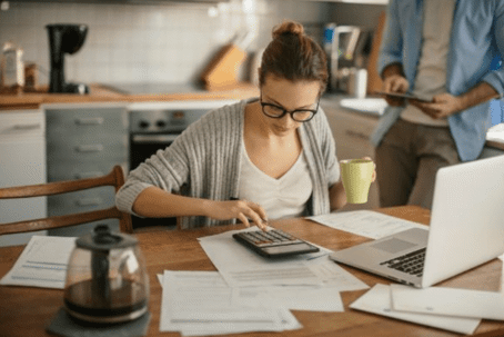 woman at kitchen counter using calculator