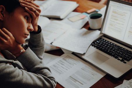 woman stressed sitting over paperwork and laptop