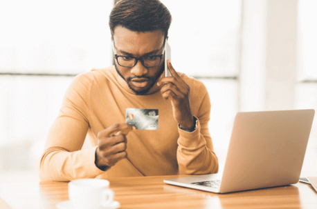 man on cell phone looking at credit card