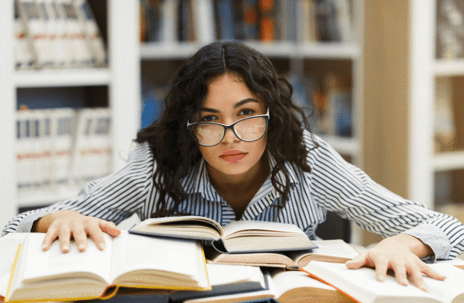 woman leaning over books in library