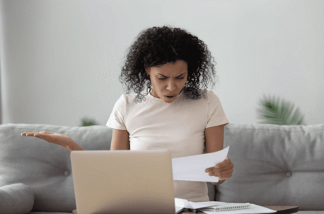 woman shocked looking at paper with laptop