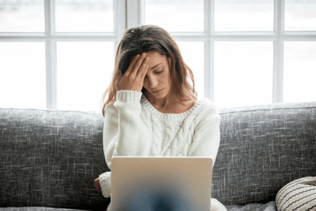 woman stressed holding head on laptop