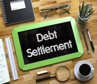 Tablet at a desk with title "Debt Settlement" written across it