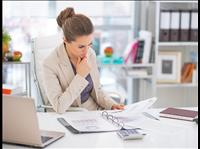 Woman sitting at desk reading over a binder