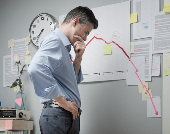 Man looking at downward trending red graph