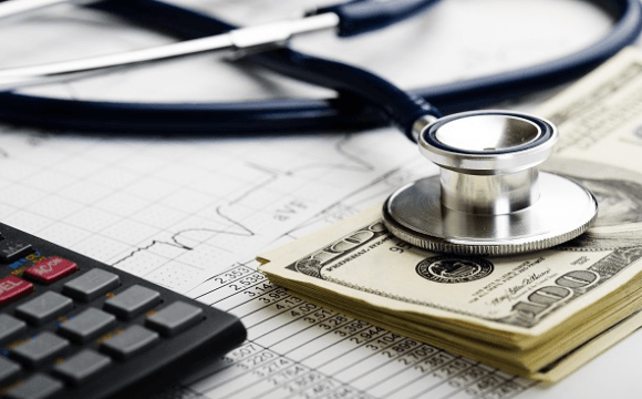Stethoscope, calculator, and stack of $100 bills set on a medical bill