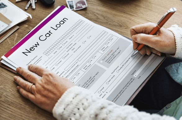 Close up of hands filling out a new car loan application 