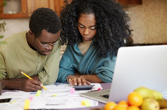 Couple reviewing budget on a desk with a calculator and a laptop