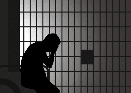 Silhouette of man sitting in a jail cell