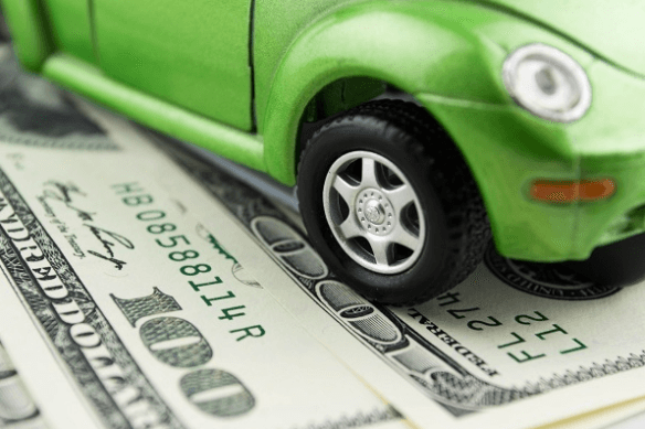 Mini green car set on top of $100 dollar bills