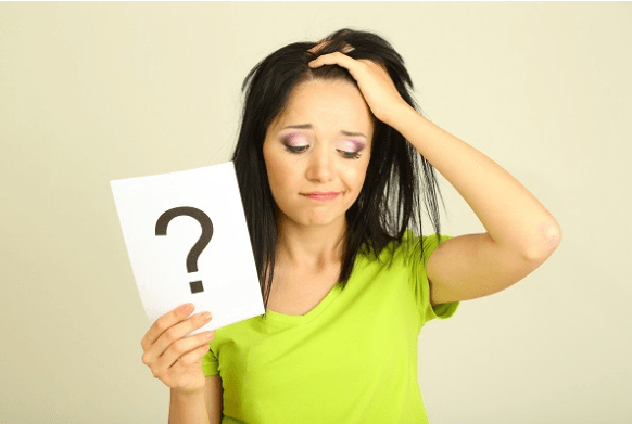 Woman in a green shirt holding up a paper with a "?" on it