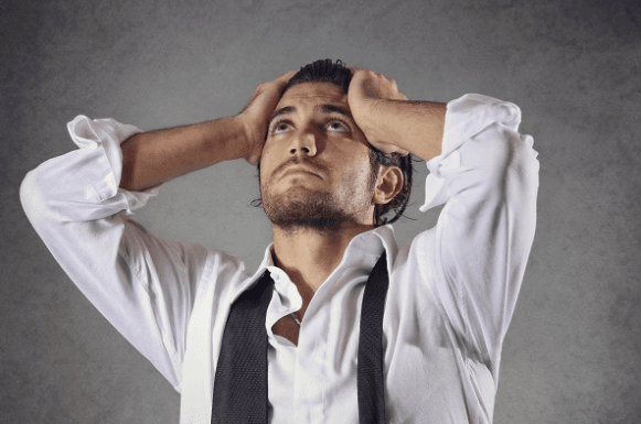 Man in a suit frustrated with hands on the side of his face