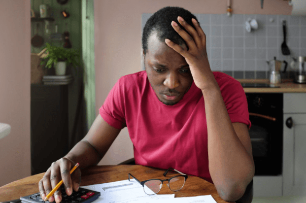 Man looking over bills with hand on his face