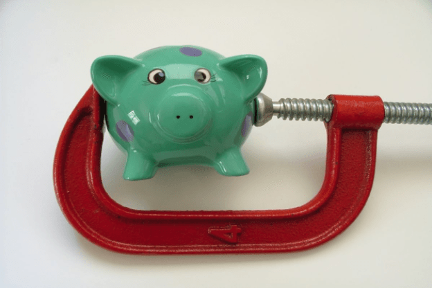 Piggy bank pressed in a red clamp