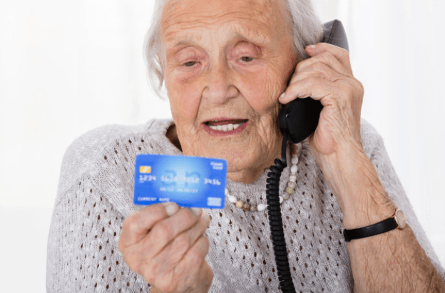 Elderly woman with telephone to her ear and a credit card in her hand