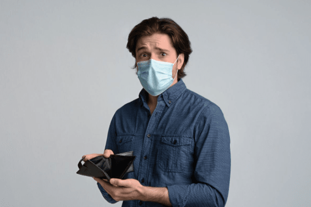 Man in a medical mask concerned with empty wallet