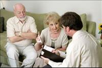 Elderly couple sitting on a couch meeting with a man in a suit