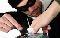 Man dressed as a robber trying to take a credit card being swiped through a credit card machine