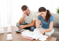 Couple stressed reviewing bills in their living room